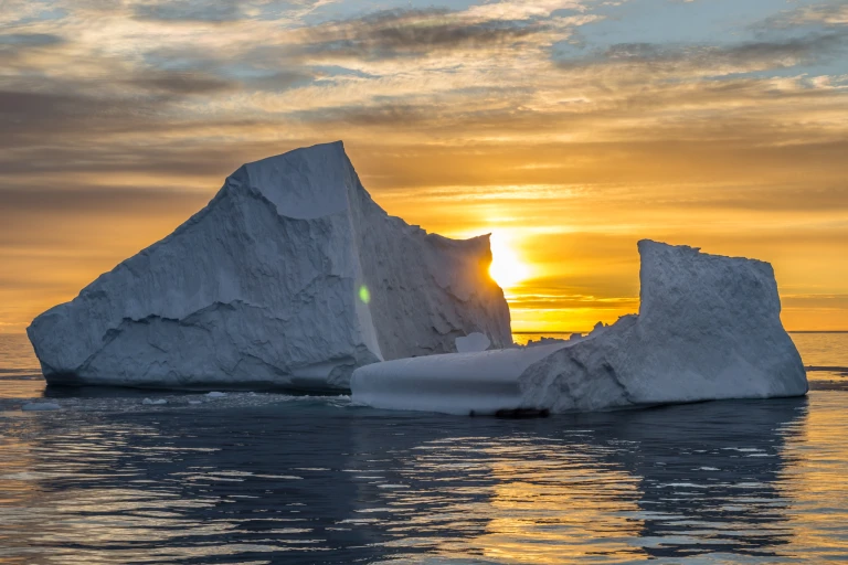 Sonnenuntergang hinter Eisberg im Ozean
