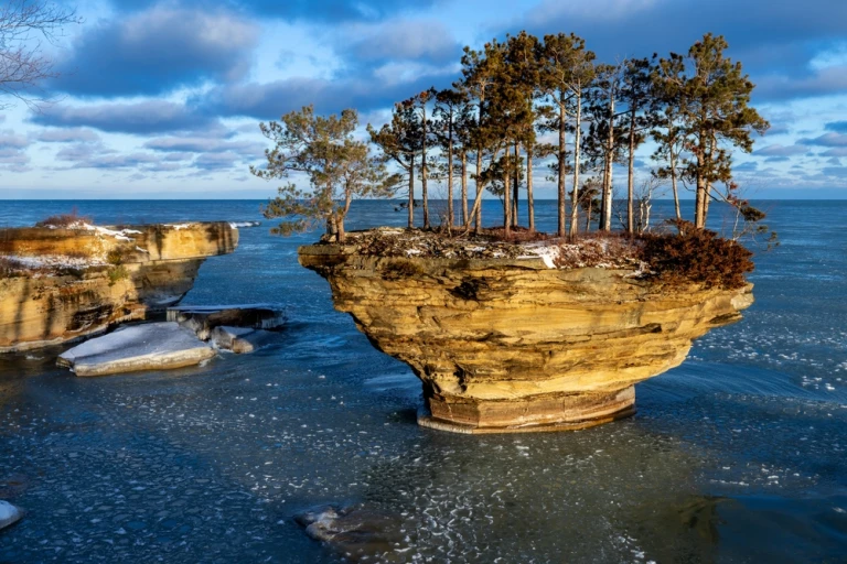 Morgensonne beleuchtet eine Felsformation am Huron-See. Der Turnip Rock ist ein beliebtes Ziel für Kajakfahrer in der Sommersaison. Im Winter beginnt ein neuer Anfang, das Pfannkucheneis muss